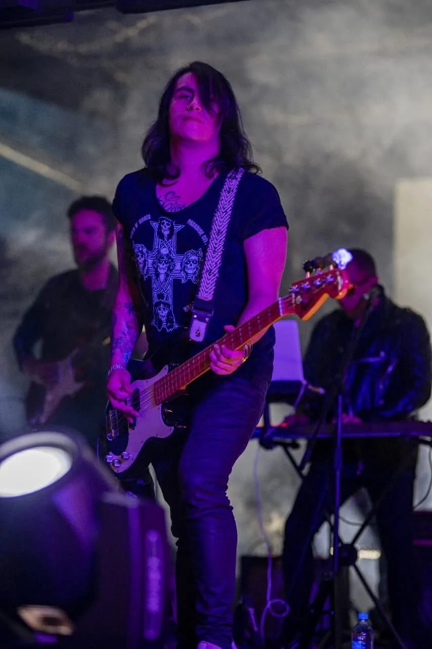 Mateo Acevedo toca el bajo en una presentación en vivo con luces moradas junto a su banda.