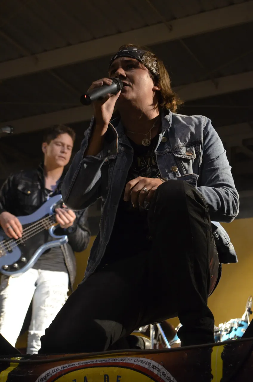 Mateo Acevedo cantando con su banda y bajista en una presentación en vivo