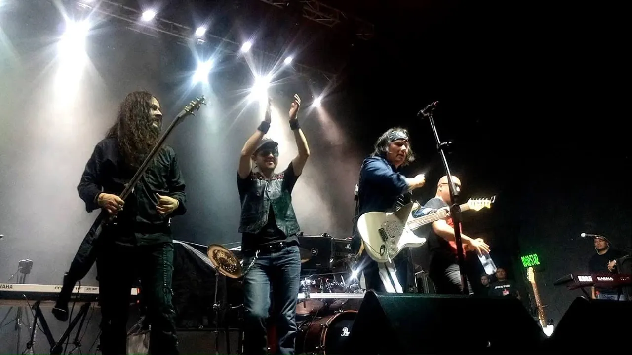 Mateo Acevedo y su banda tocando en vivo sobre una tarima de festival bajo potentes luces blancas.