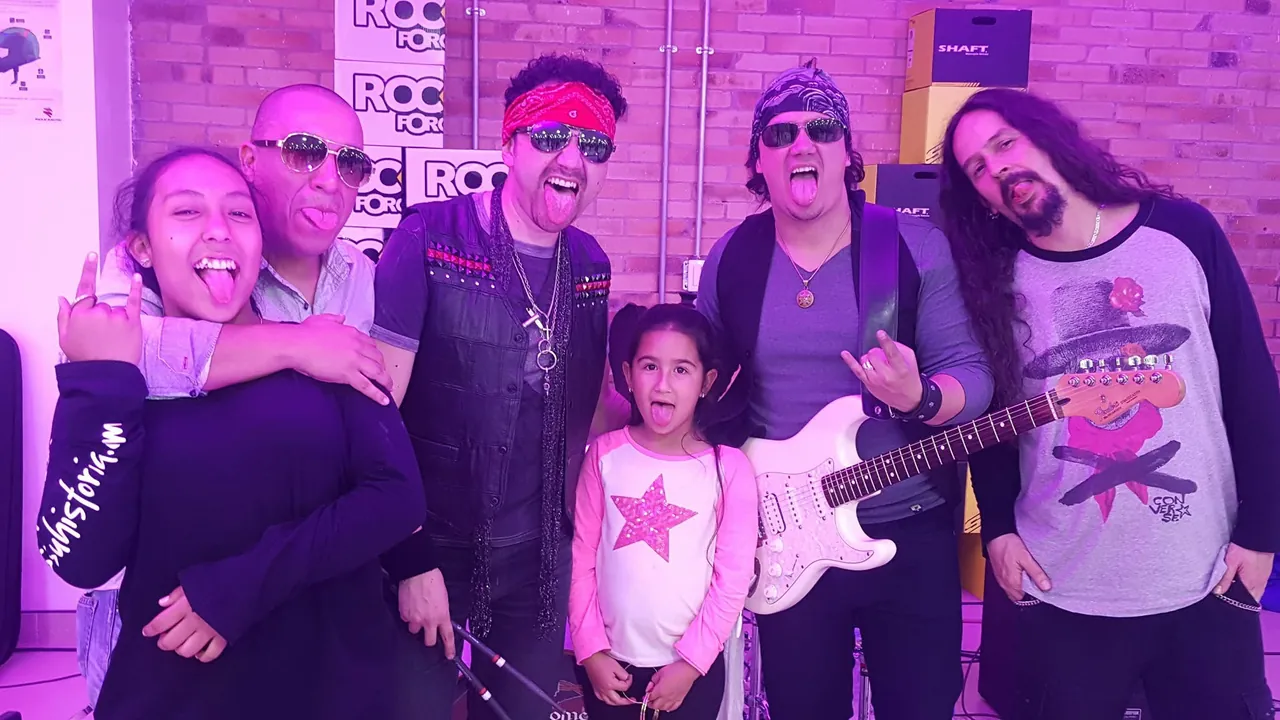 Mateo Acevedo y su banda posan divertidos junto a varios asistentes durante una sesión de rock en vivo.