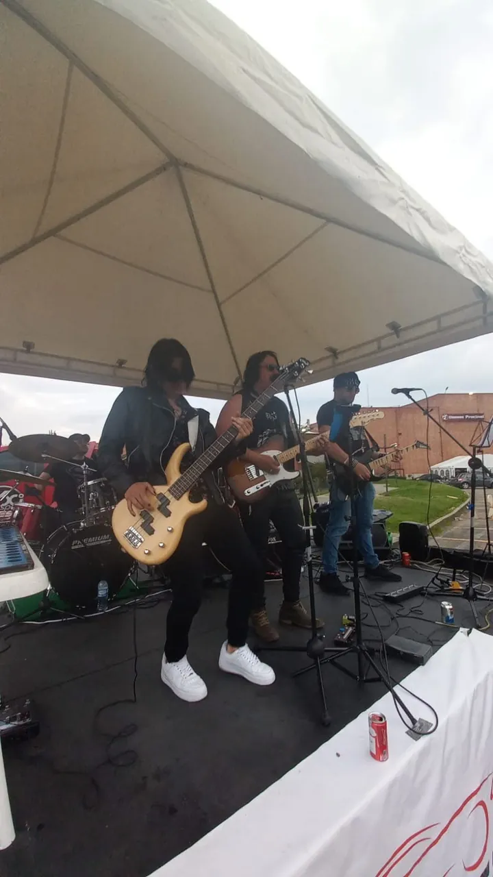 Mateo Acevedo y su banda de rock tocan en vivo sobre una tarima al aire libre durante un concierto.