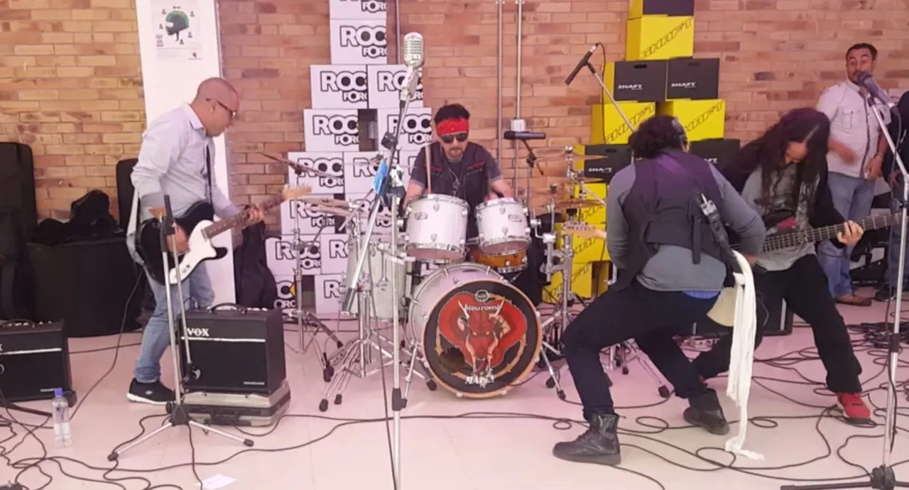 Mateo Acevedo y su banda durante una sesión de rock en vivo frente a un muro de ladrillo.