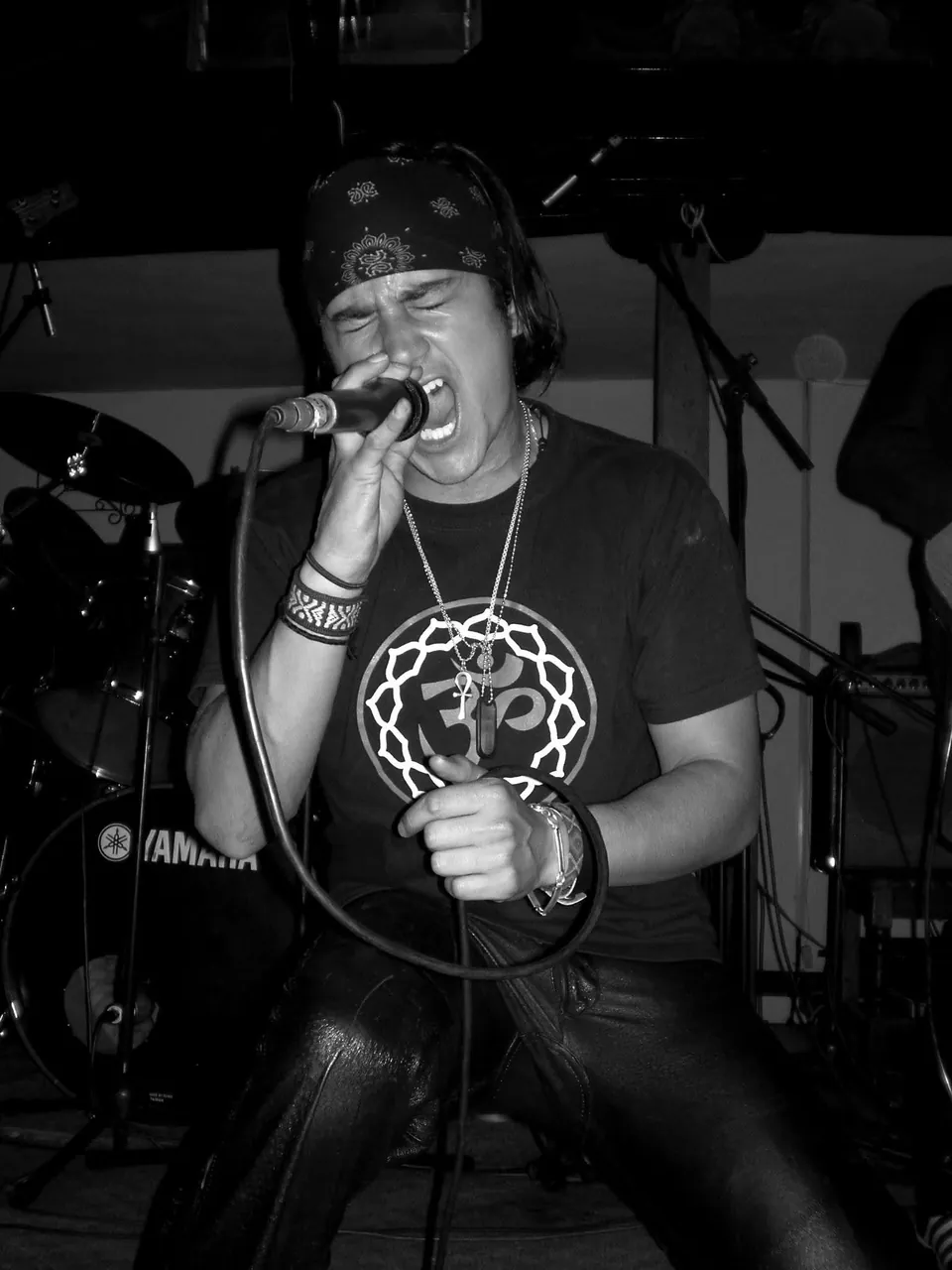 Retrato en blanco y negro de Mateo Acevedo cantando con intensidad frente al micrófono en un concierto.