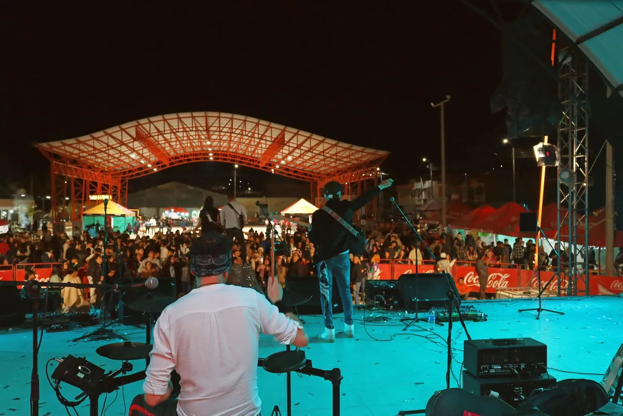 Mateo Acevedo y su banda tocan en una tarima al aire libre frente a un público nocturno.