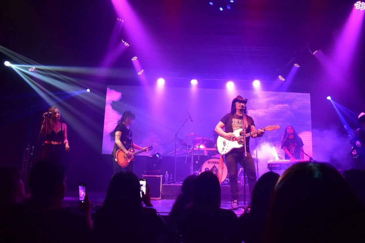 Mateo Acevedo y su banda en concierto sobre el escenario mientras el público graba la presentación.