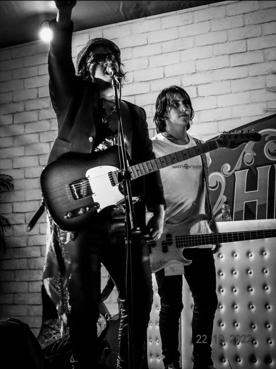Mateo Acevedo canta con el brazo en alto en una presentación en vivo, foto en blanco y negro.
