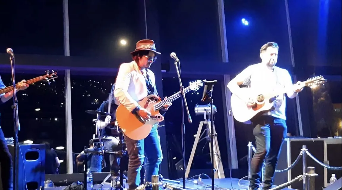 Mateo Acevedo toca la guitarra eléctrica frente al micrófono durante un concierto en vivo.