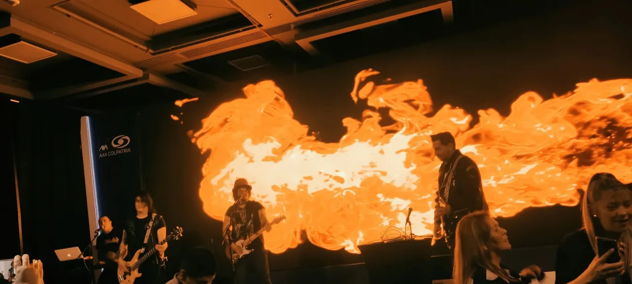 Mateo Acevedo y su banda en un evento corporativo con una pantalla LED de llamas.