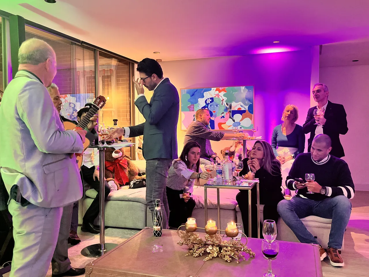 Evento social privado con música en vivo y servicio de bebidas, invitados en salas con luz morada.