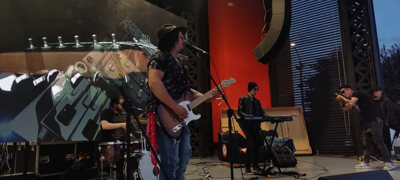 Mateo Acevedo se presenta en la tarima de un festival al aire libre con pantalla gigante.