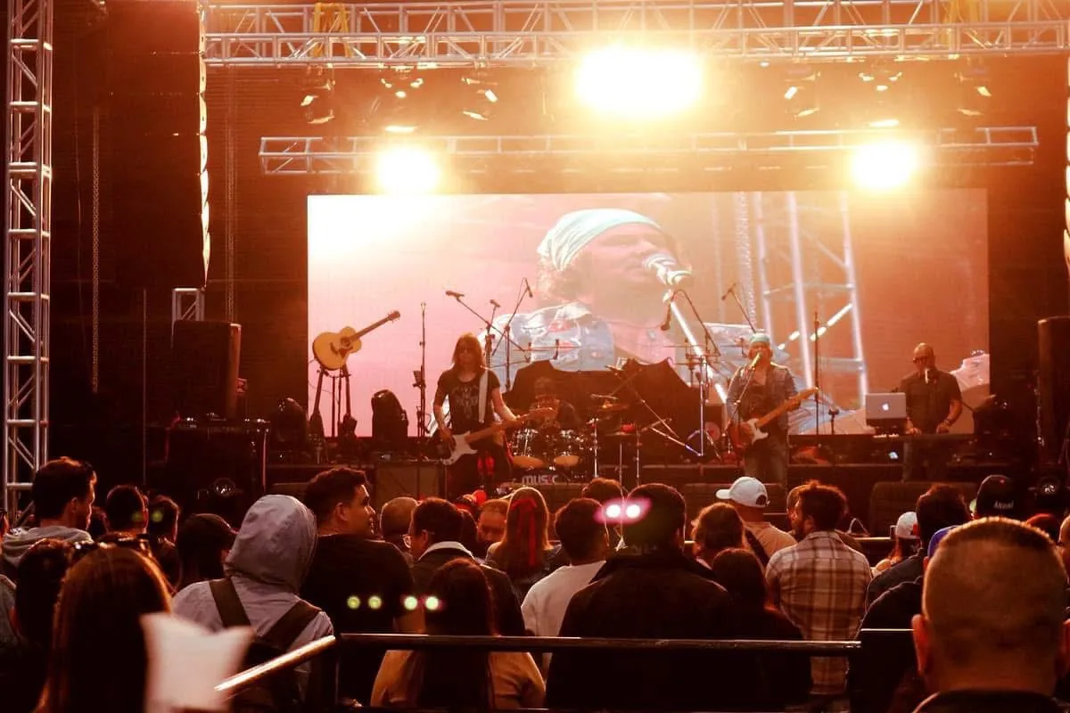 Mateo Acevedo y su banda en un festival con gran pantalla LED y un público numeroso.