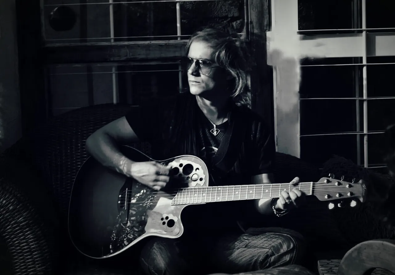 Mateo Acevedo tocando guitarra acústica en una foto en blanco y negro