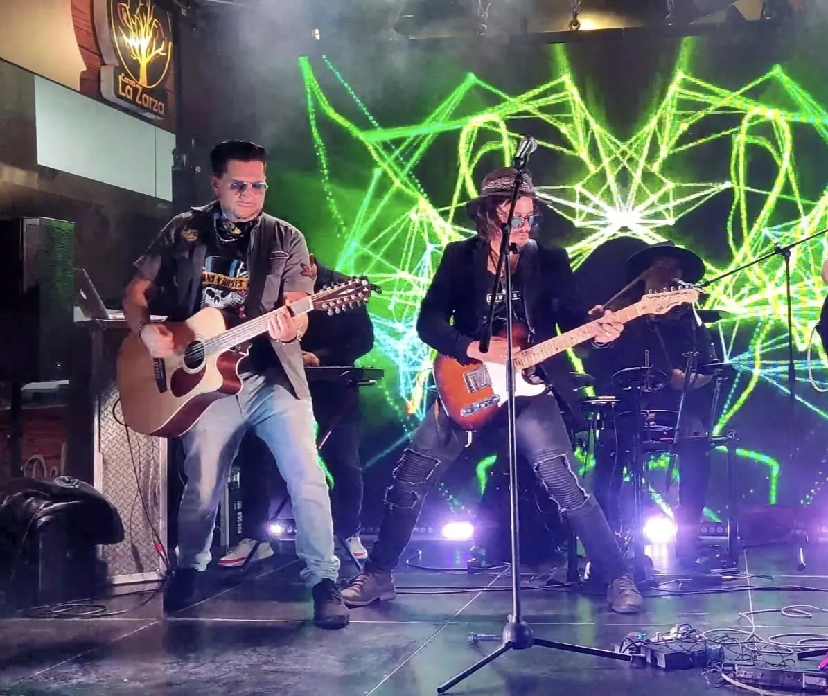 Mateo Acevedo y otro guitarrista tocan guitarra acústica y eléctrica en un show en vivo dentro de un bar.