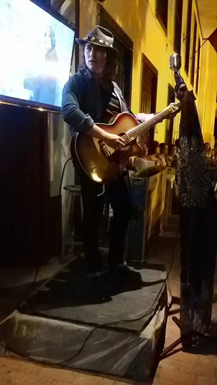 Mateo Acevedo toca la guitarra acústica y canta al micrófono vintage en una presentación acústica íntima.