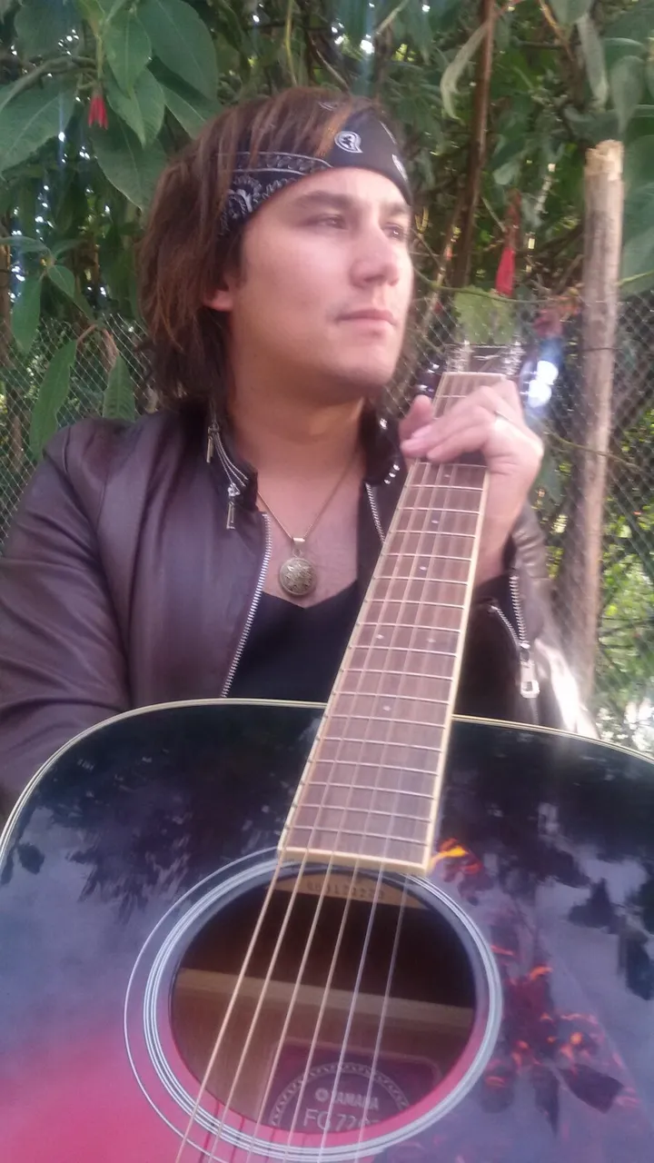 Mateo Acevedo con chaqueta de cuero sosteniendo una guitarra acústica al aire libre