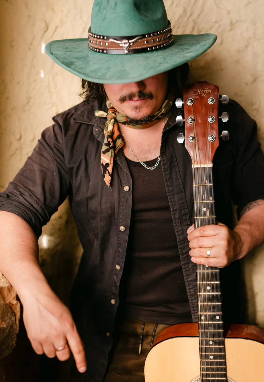 Mateo Acevedo con sombrero sosteniendo una guitarra acústica