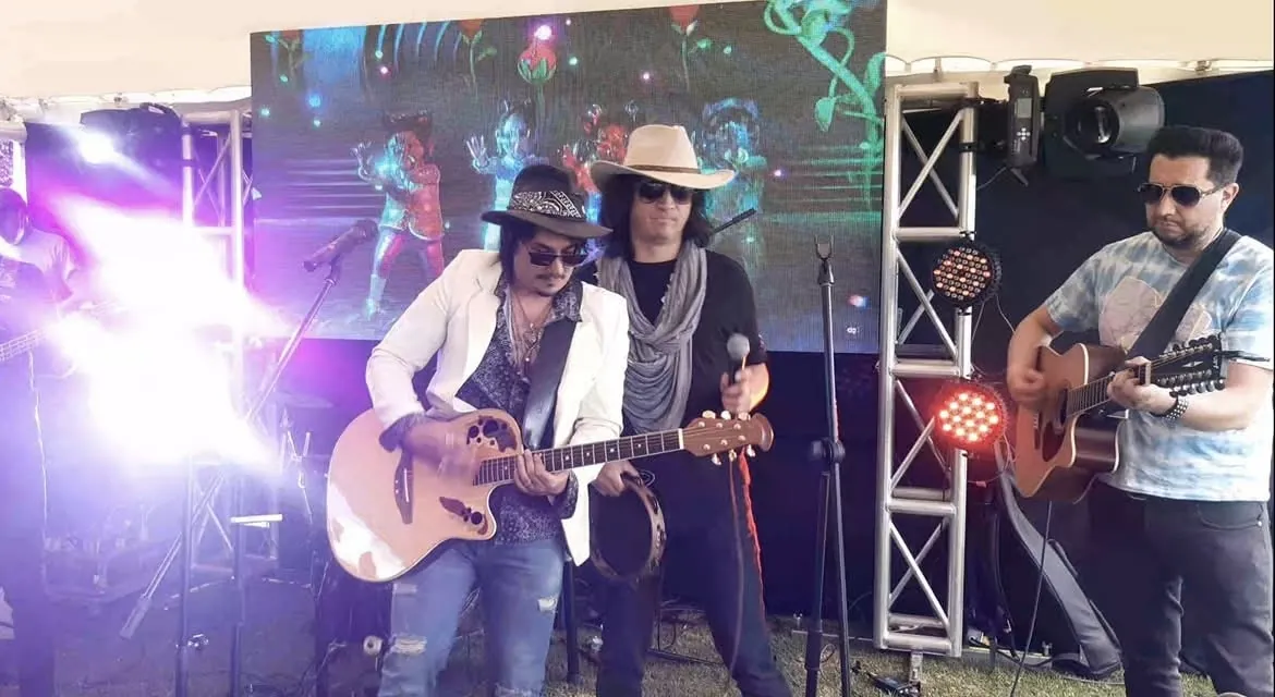 Mateo Acevedo toca la guitarra acústica sobre la tarima con luces y estructuras de un concierto en vivo.