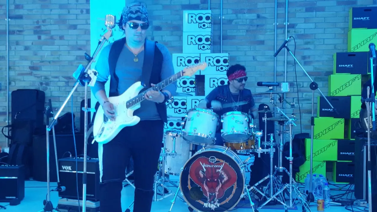 Mateo Acevedo toca su guitarra eléctrica blanca junto a su banda en una presentación al aire libre.