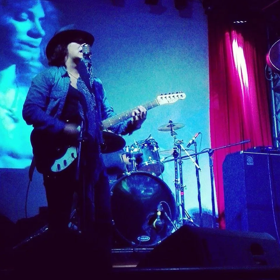 Mateo Acevedo tocando guitarra eléctrica en tarima con luces de concierto