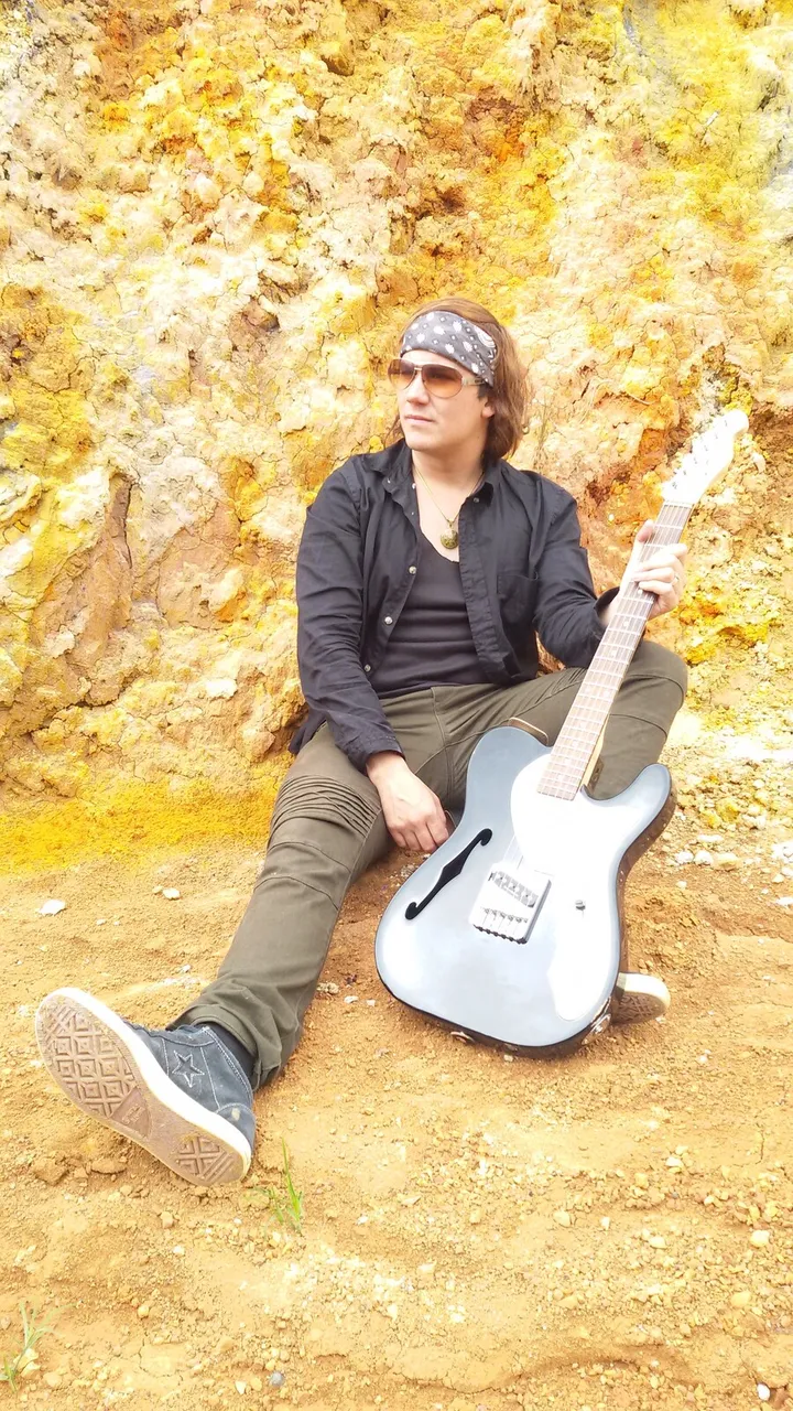 Mateo Acevedo con guitarra eléctrica sentado sobre fondo otoñal