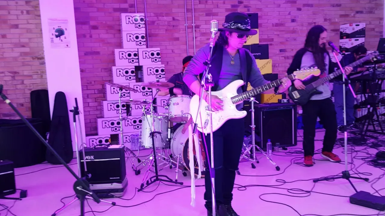 Mateo Acevedo toca la guitarra eléctrica con sombrero durante una sesión de rock en vivo con su banda.