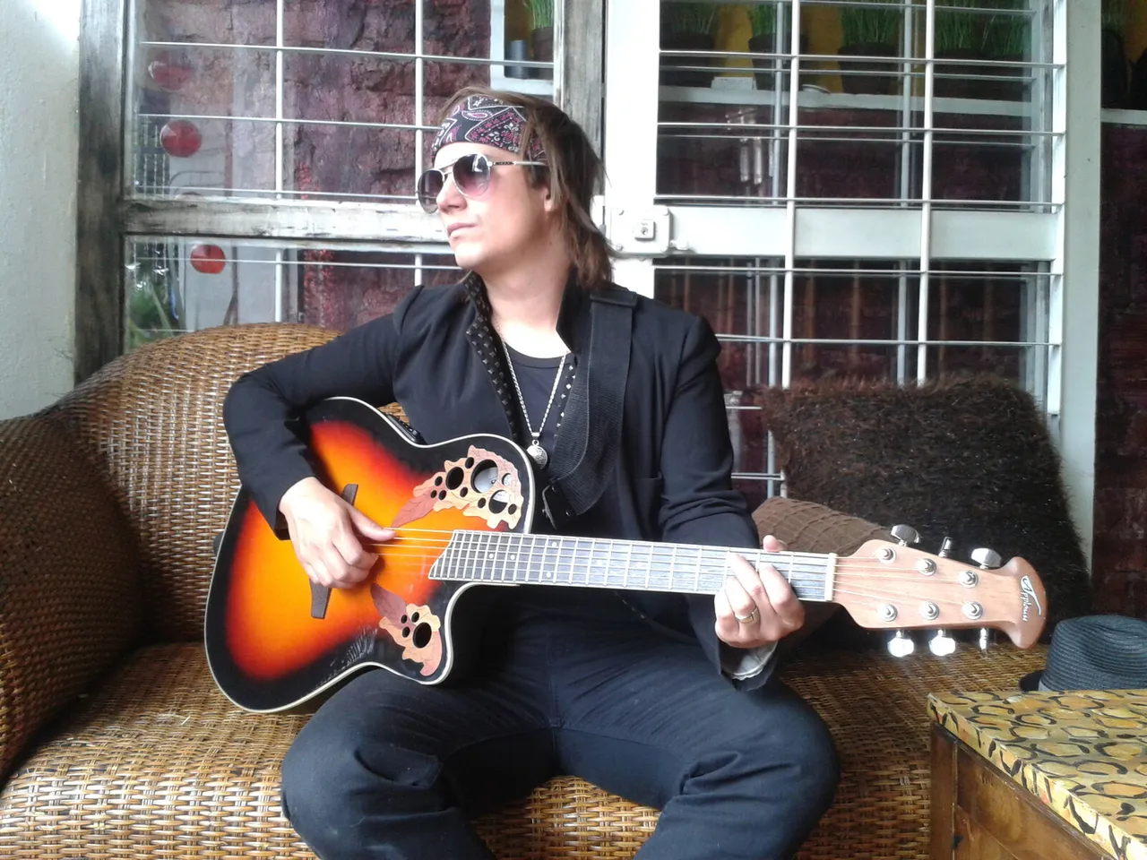 Mateo Acevedo tocando guitarra eléctrica sentado junto a una ventana