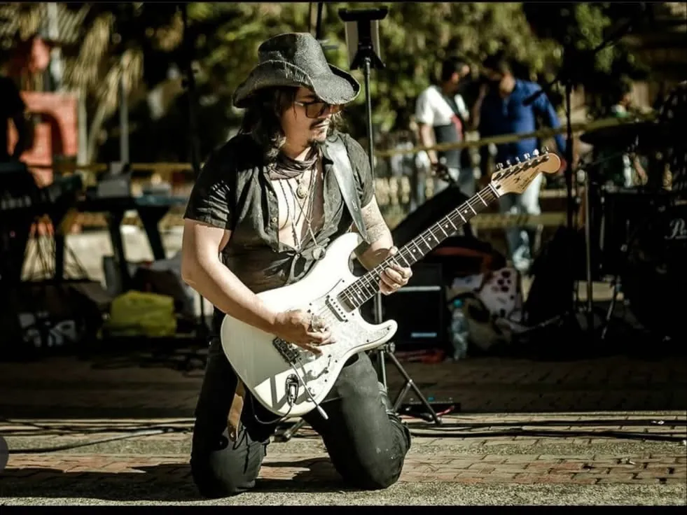 Mateo Acevedo toca la guitarra eléctrica blanca durante un show en vivo nocturno.