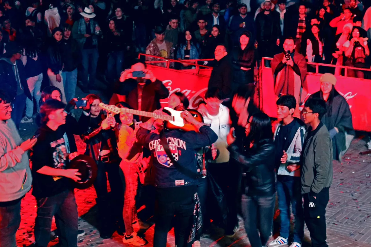 Mateo Acevedo toca la guitarra en medio del público durante un concierto al aire libre.