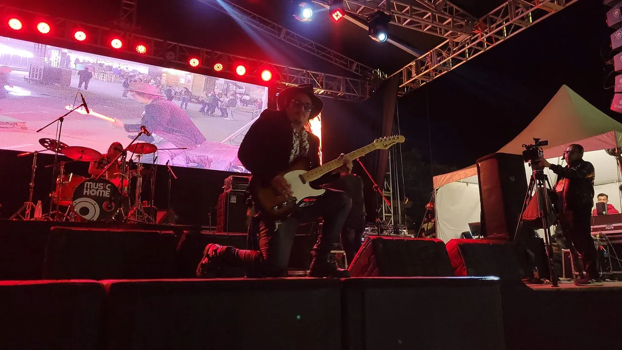 Mateo Acevedo toca la guitarra con energía sobre la tarima durante un festival nocturno.