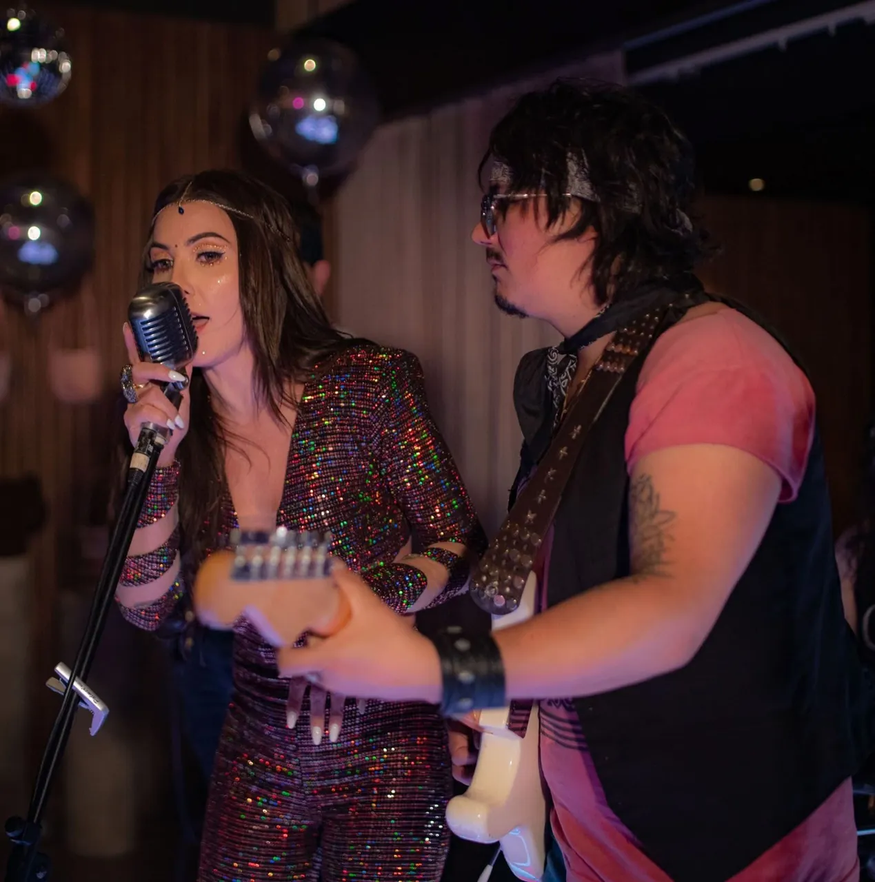 Mateo Acevedo toca la guitarra eléctrica junto a la cantante de la banda durante un show en vivo.