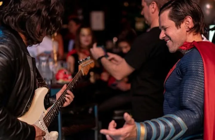 Mateo Acevedo tocando guitarra eléctrica frente a un invitado disfrazado durante un show temático en vivo.