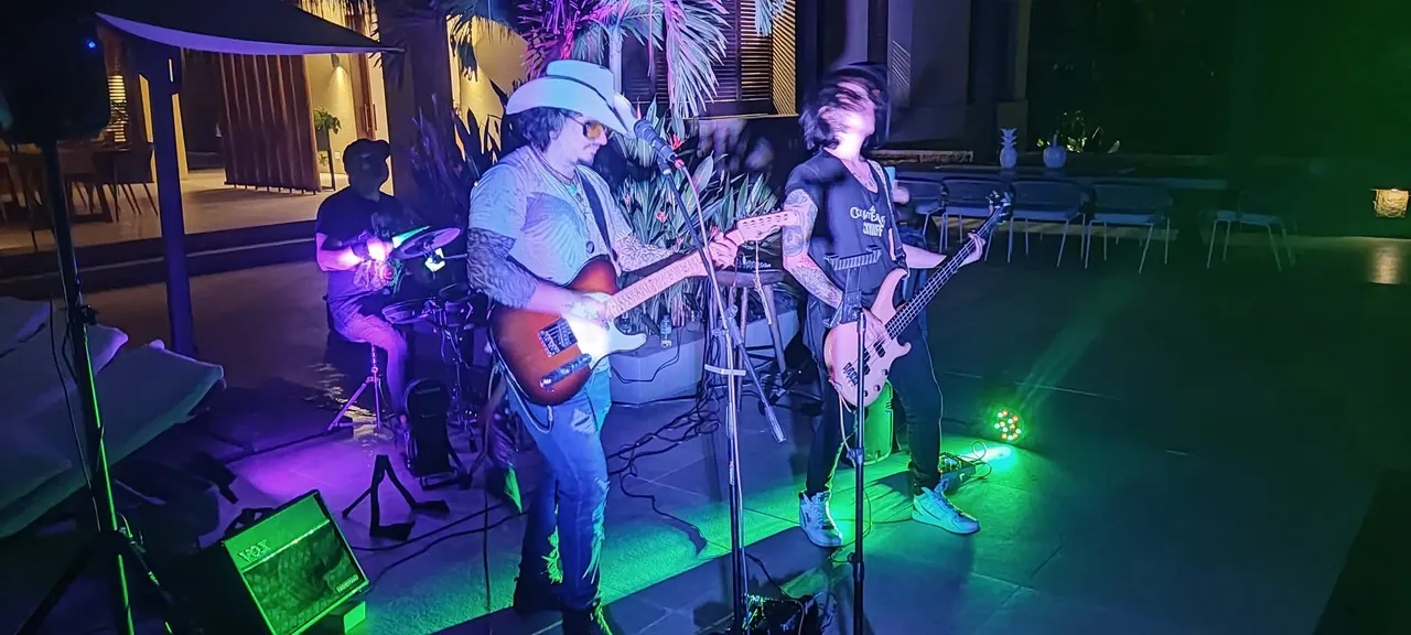 Mateo Acevedo toca la guitarra con sombrero junto a su banda en una presentación nocturna en terraza.