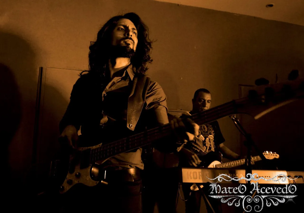 Mateo Acevedo toca la guitarra con cabello largo y chaleco de cuero durante un concierto de rock en vivo.
