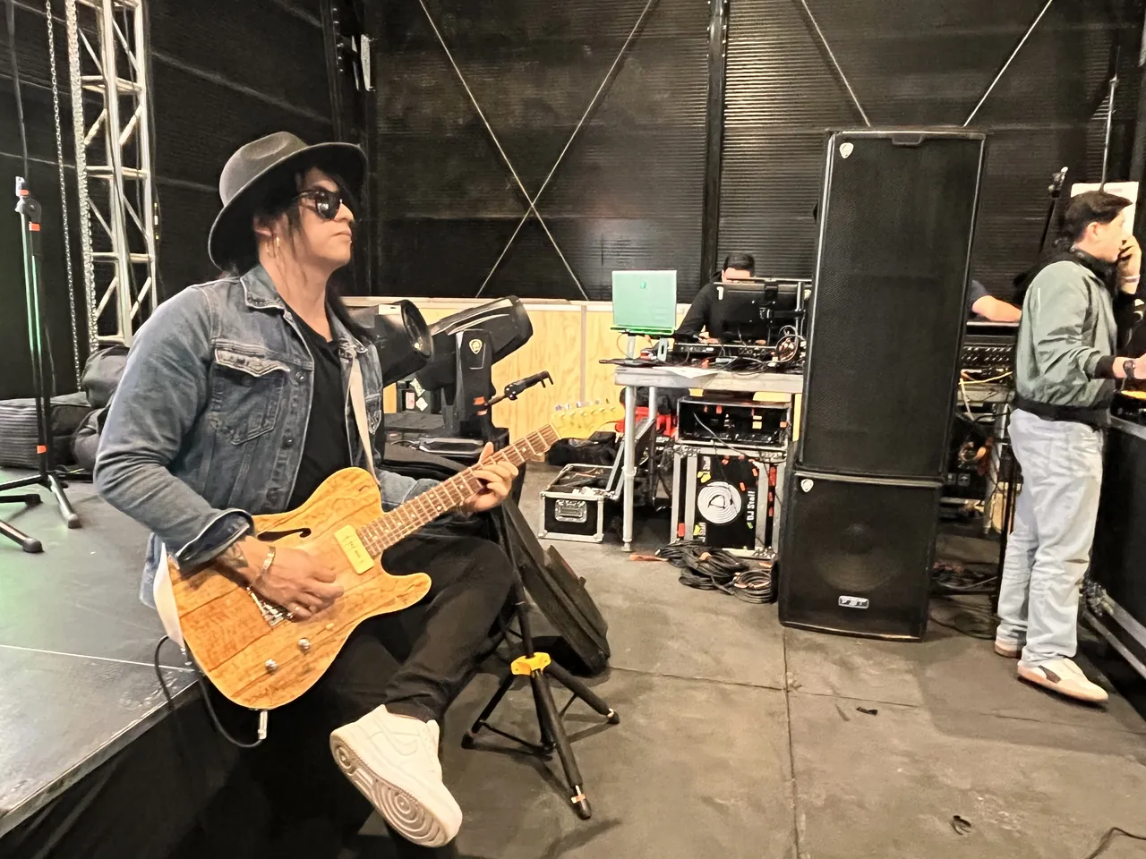 Mateo Acevedo tocando su guitarra eléctrica junto al equipo de sonido tras bambalinas en un evento.