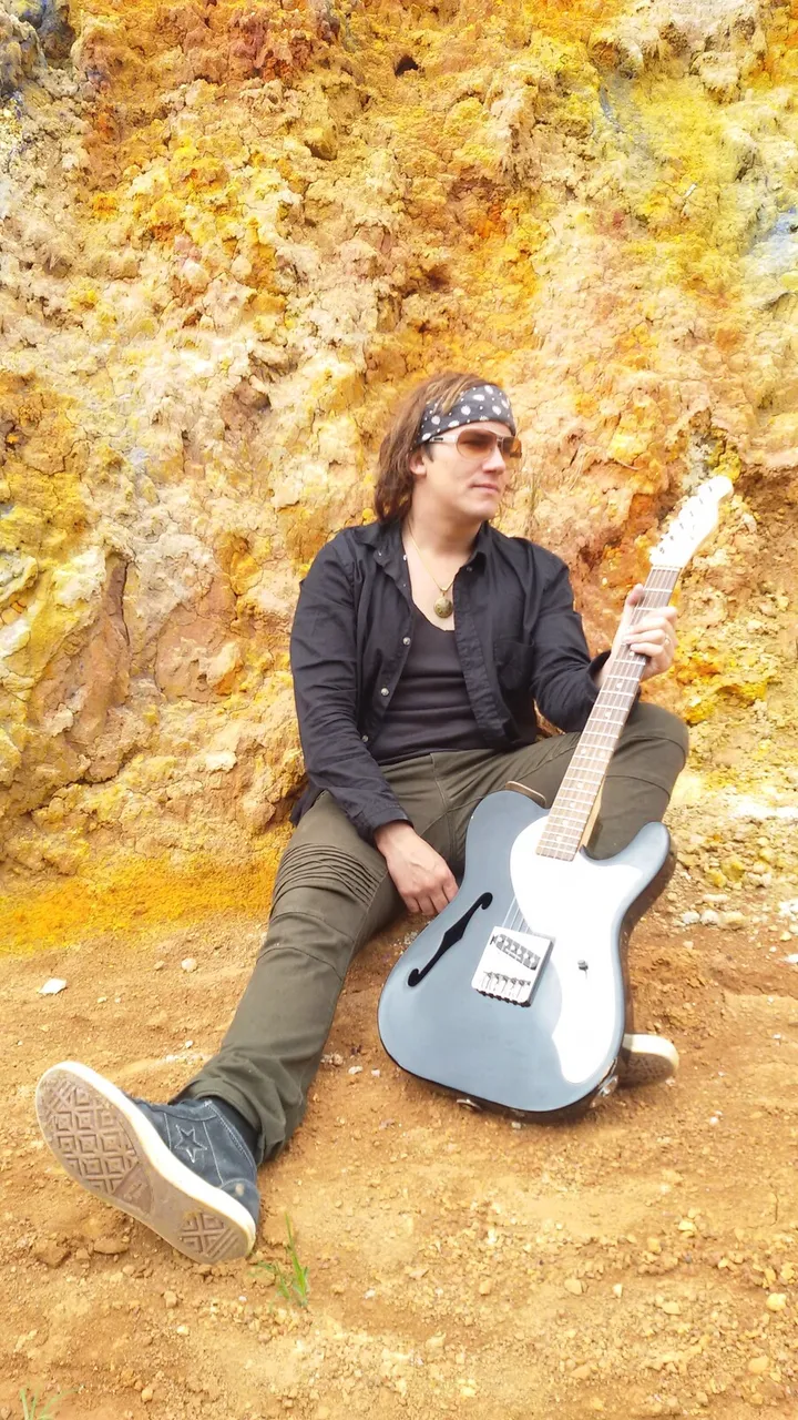 Mateo Acevedo con guitarra eléctrica sobre un fondo de paisaje otoñal