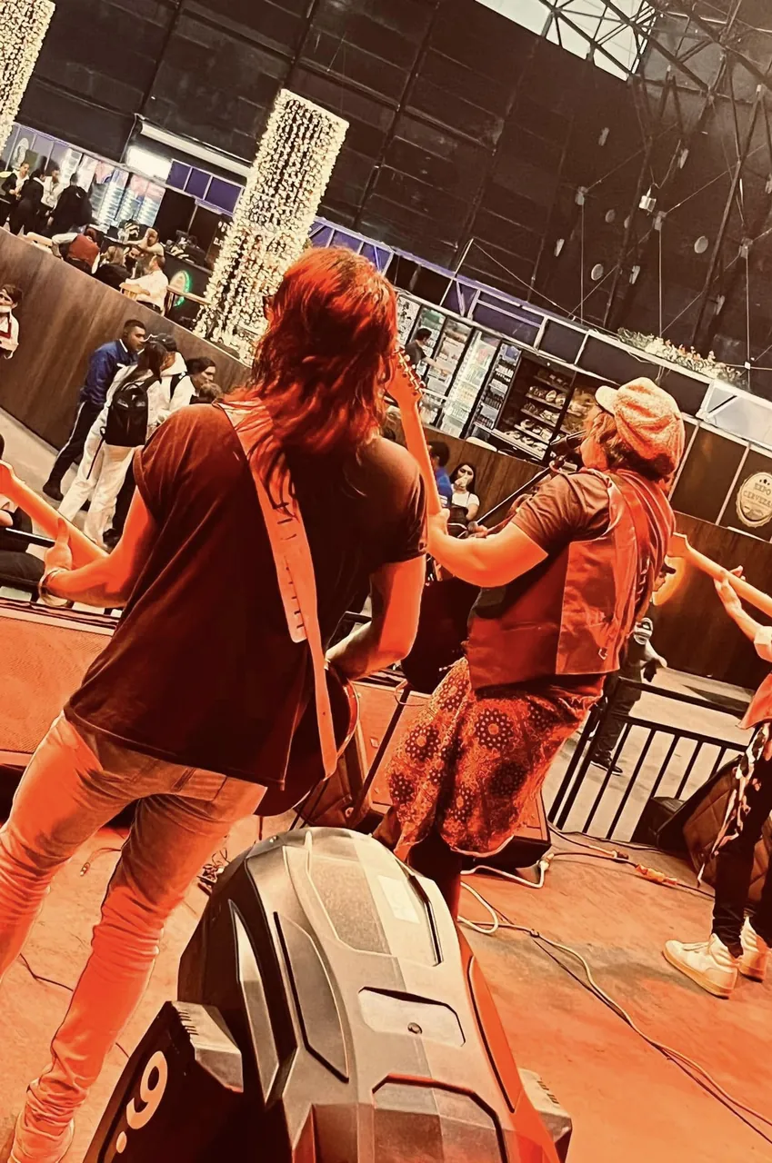 Mateo Acevedo y un músico de su banda en una presentación en vivo con luces cálidas.