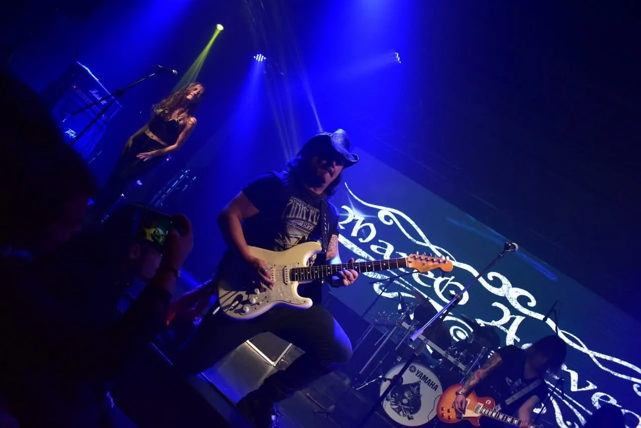 Mateo Acevedo, guitarrista de rock, en plena presentación sobre la tarima iluminada de un concierto.
