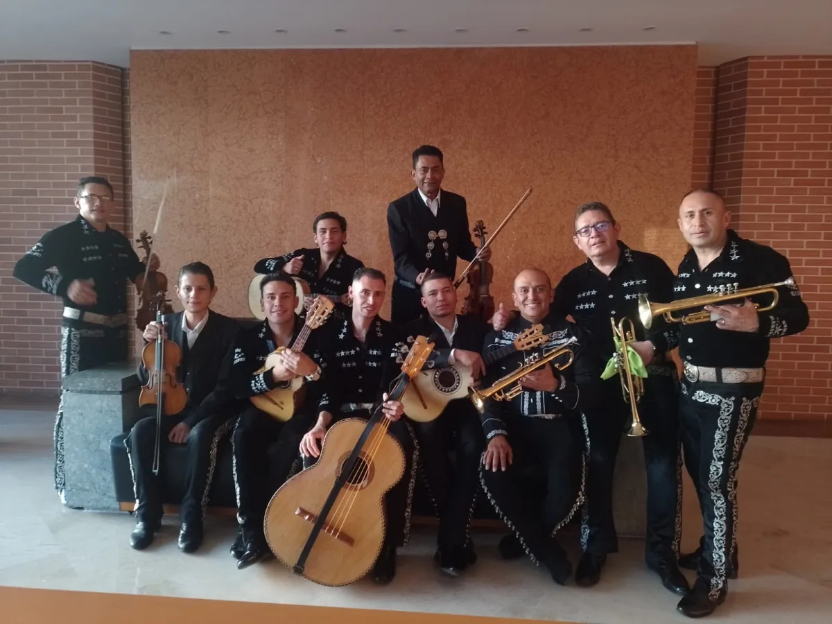 Grupo de mariachi completo tocando en vivo con trompetas, violines y guitarrón en un evento en Bogotá