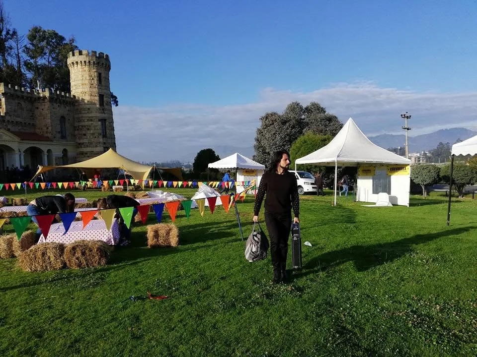 Mateo Acevedo llega con sus equipos a un evento al aire libre, con un castillo y banderines al fondo.