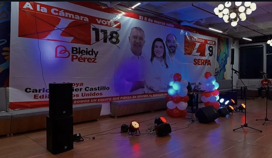 Montaje de sonido e iluminación con tarima y telón de fondo para un evento.