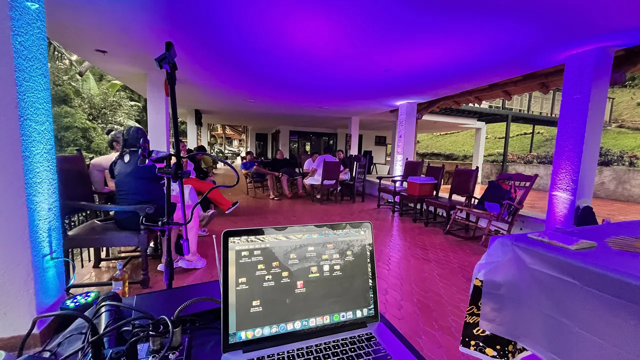 Presentación de música en vivo en la terraza de una finca, con invitados sentados y luces moradas de ambiente.