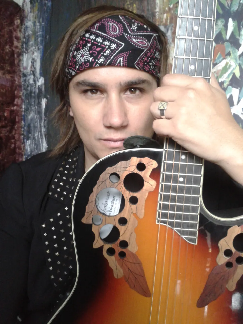 Mateo Acevedo con pañoleta sosteniendo su guitarra en un retrato