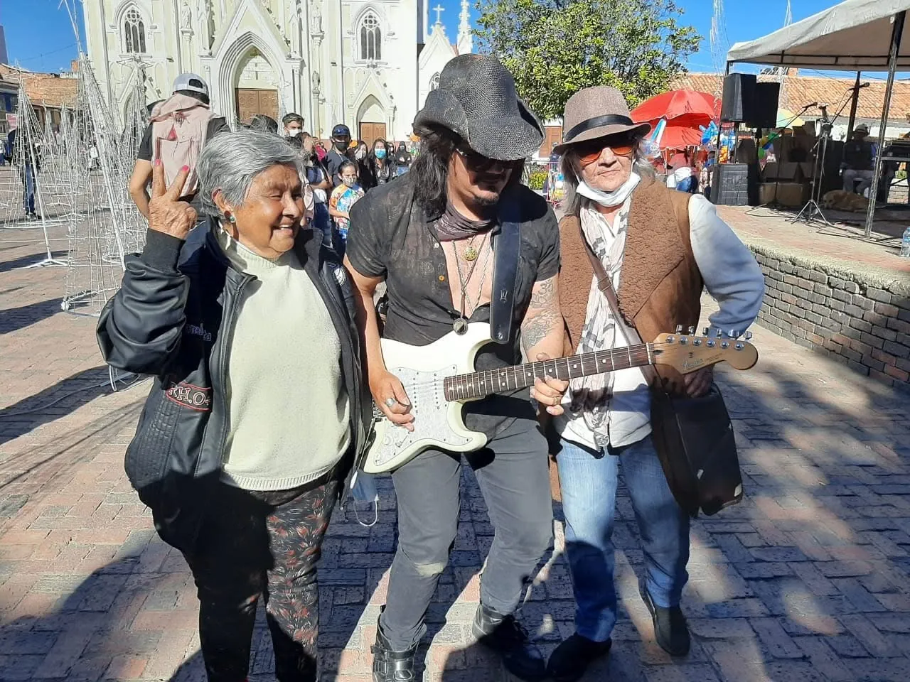 Mateo Acevedo toca la guitarra eléctrica en una presentación al aire libre rodeado del público.