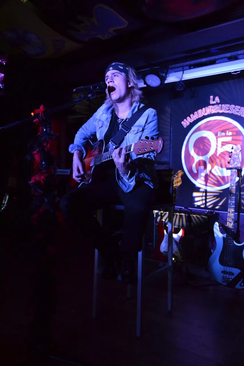 Mateo Acevedo cantando en vivo en el escenario de un bar