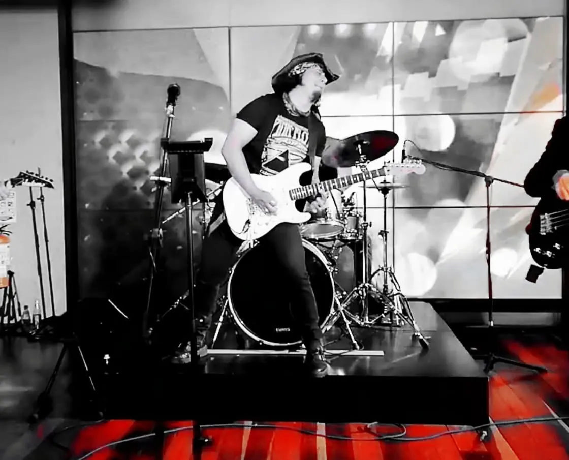 Mateo Acevedo en plena presentación de rock en vivo, tocando guitarra eléctrica con energía sobre la tarima.