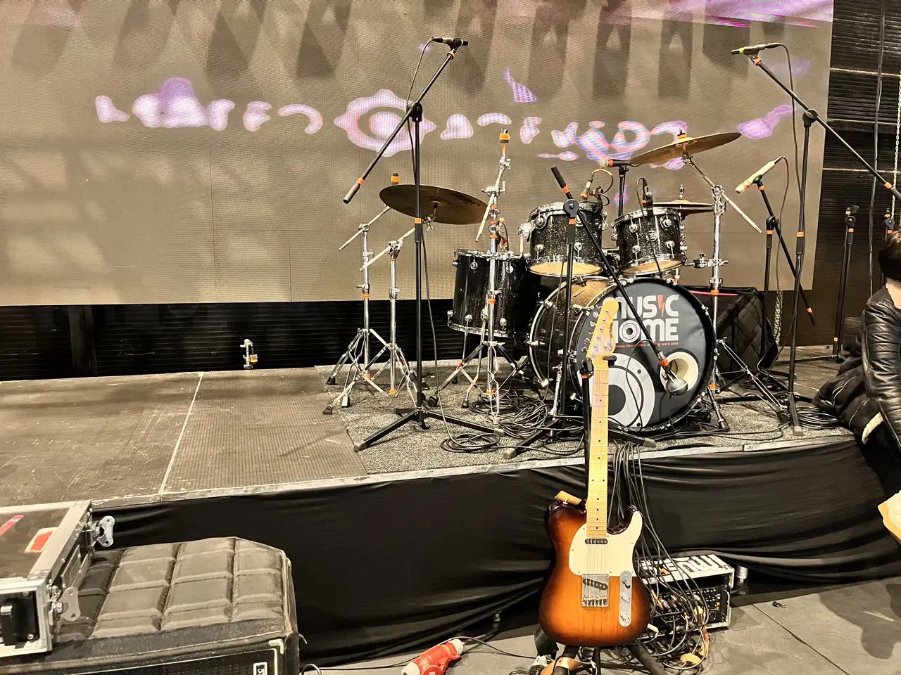 Montaje de banda en tarima con batería, guitarra eléctrica y micrófonos en una producción musical en Bogotá