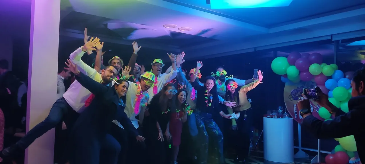 Público eufórico con accesorios neón y los brazos en alto durante una fiesta animada por la banda.