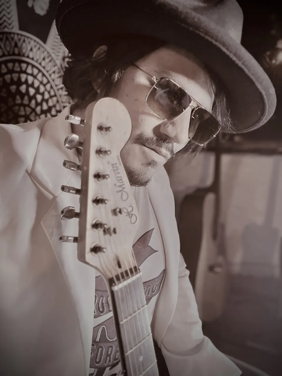 Retrato artístico en blanco y negro de Mateo Acevedo con sombrero y guitarra