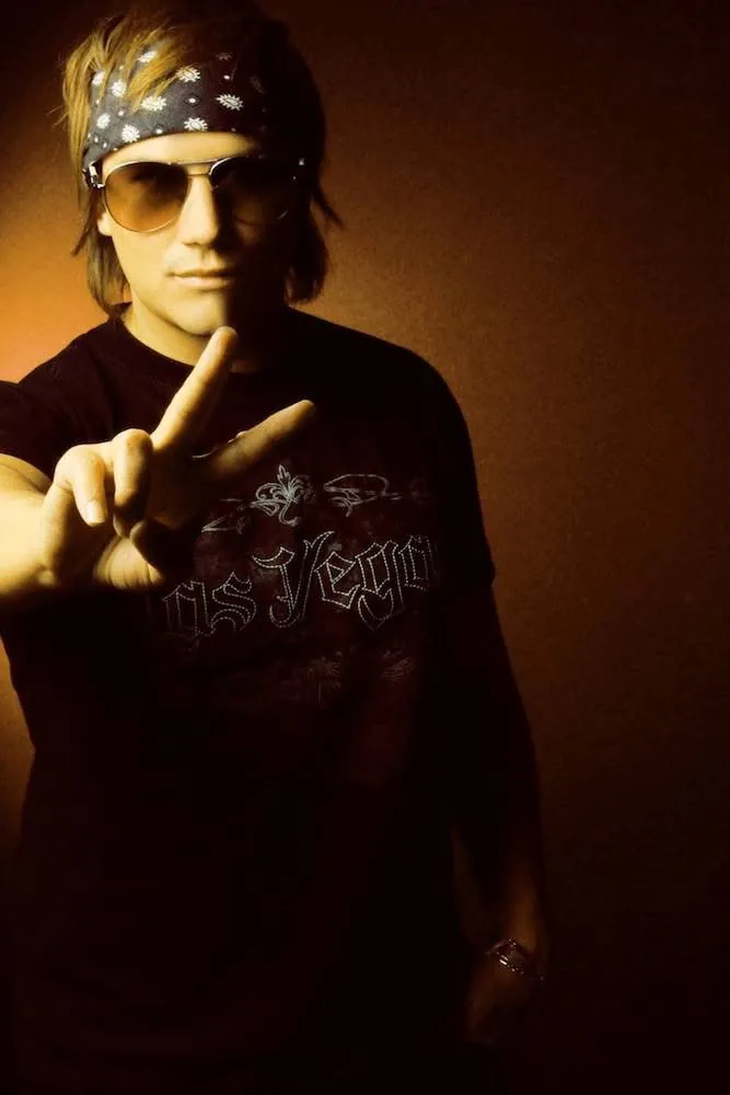 Retrato de estudio de Mateo Acevedo con gafas de sol y pañoleta haciendo el signo de la paz.