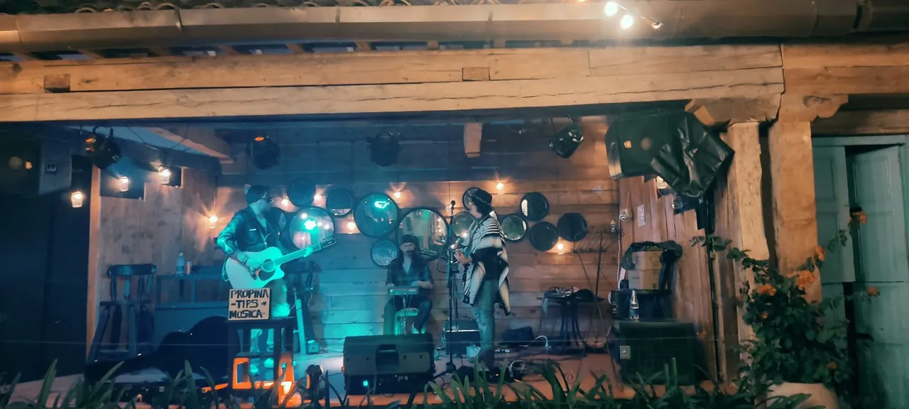Mateo Acevedo en un show acústico íntimo con ruana en un bar de ambiente rústico.